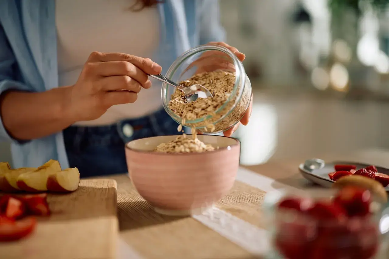 Préparation d'un petit-déjeuner sain avec des flocons d'avoine, rappelant le bon rendement avoine hectare. Des fruits frais sont à proximité.