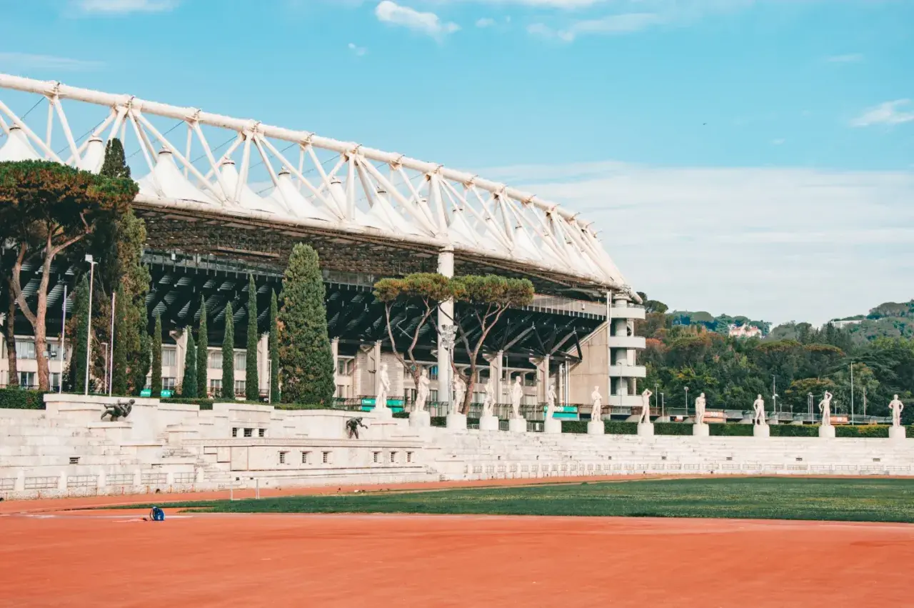 Stadion w Rzymie z rzędami rzeźb i zielenią.