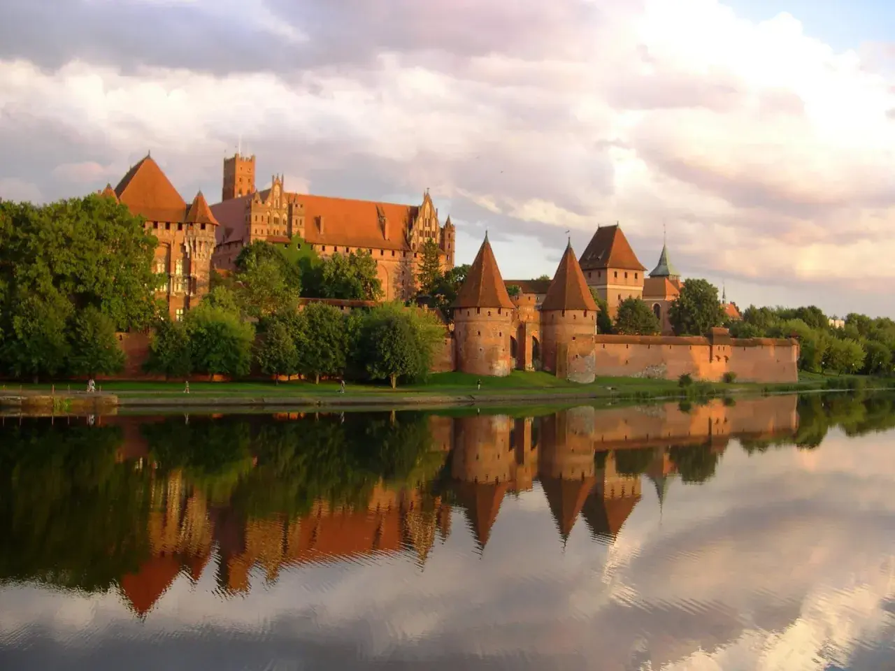 Malbork, jeden z największych zamków w Europie, odbija się w spokojnej wodzie.