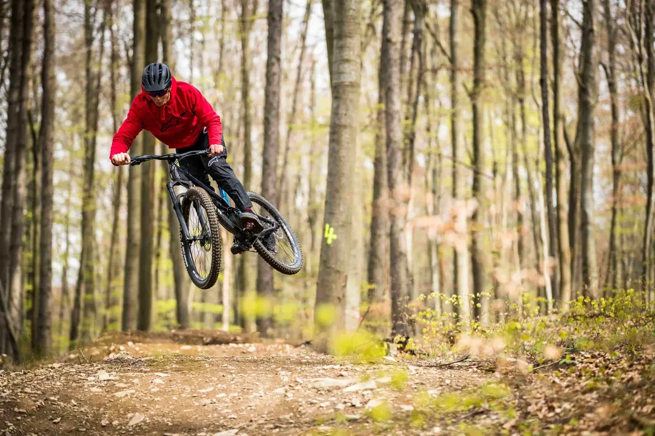 Mountainbiker springt in einem Bikepark in Tschechien über eine Schanze.