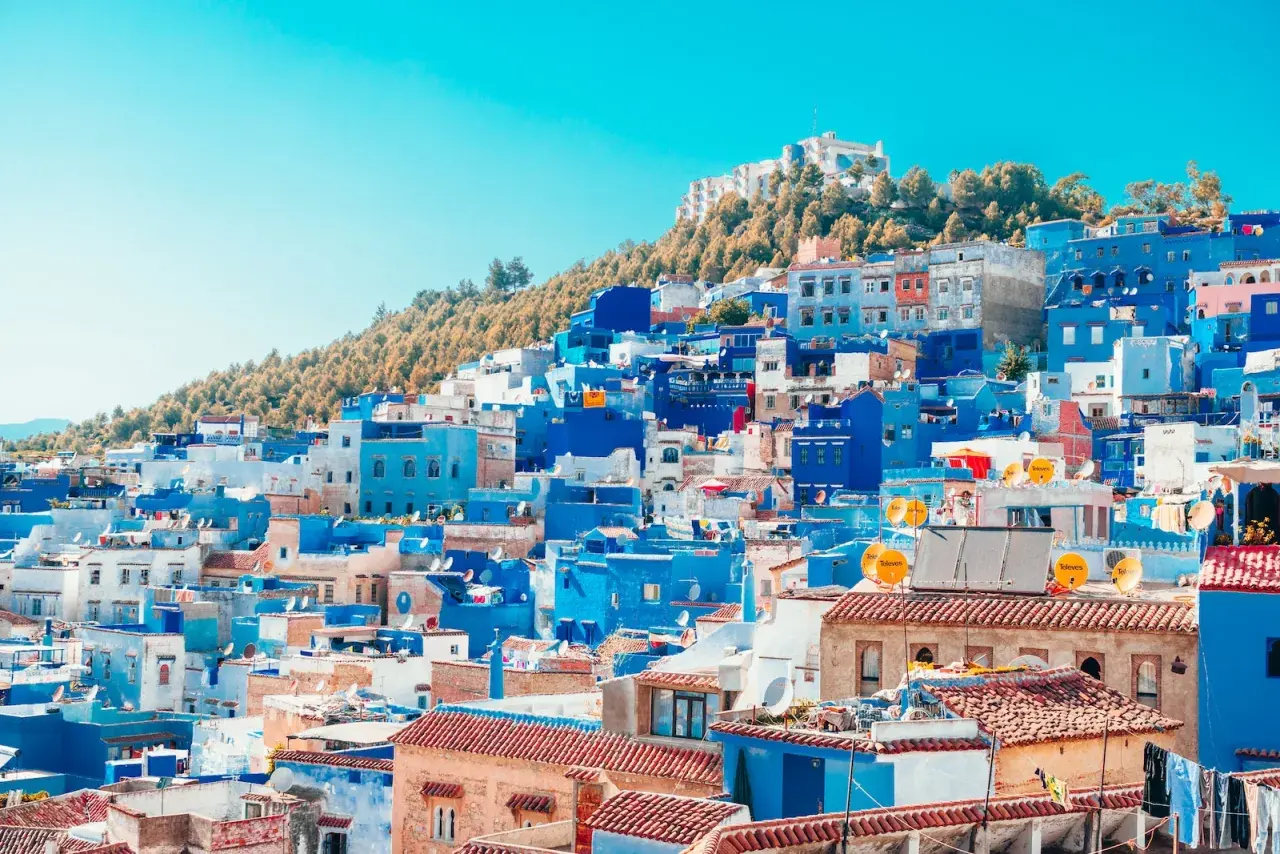 Widok na niebieskie i białe budynki miasta Chefchaouen w Maroku, na tle wzgórza.