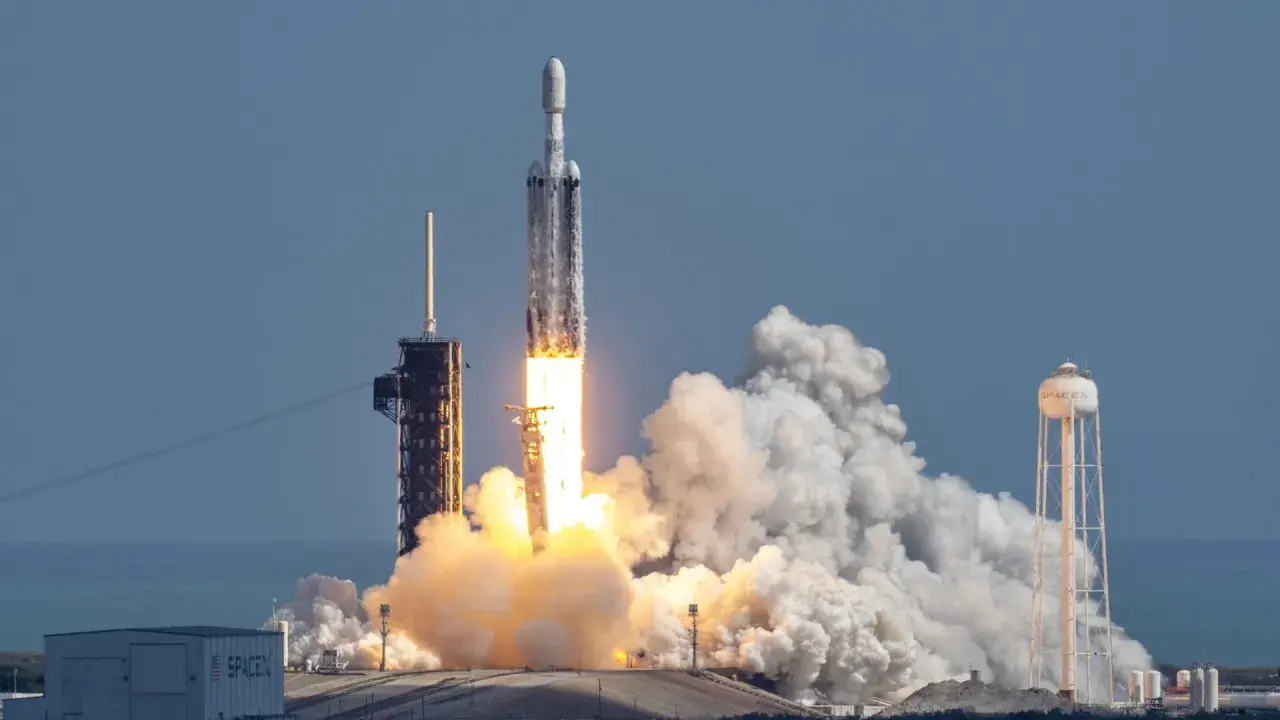 Rakieta Falcon Heavy SpaceX startuje, wzbijając się w niebo z potężnym płomieniem i kłębami dymu.