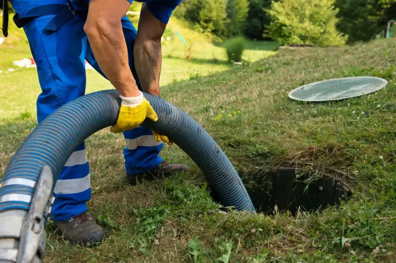 Pracownik w żółtych rękawicach obsługuje wąż do wywozu szamba. Sprawdź nasz wywóz szamba cennik i zadbaj o czystość.