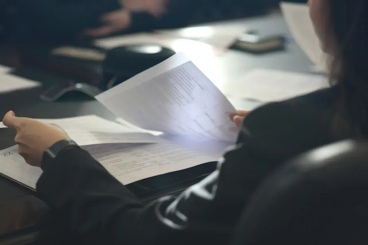 Osoba przegląda dokumenty, analizując pozaszkolne formy edukacji PKD.