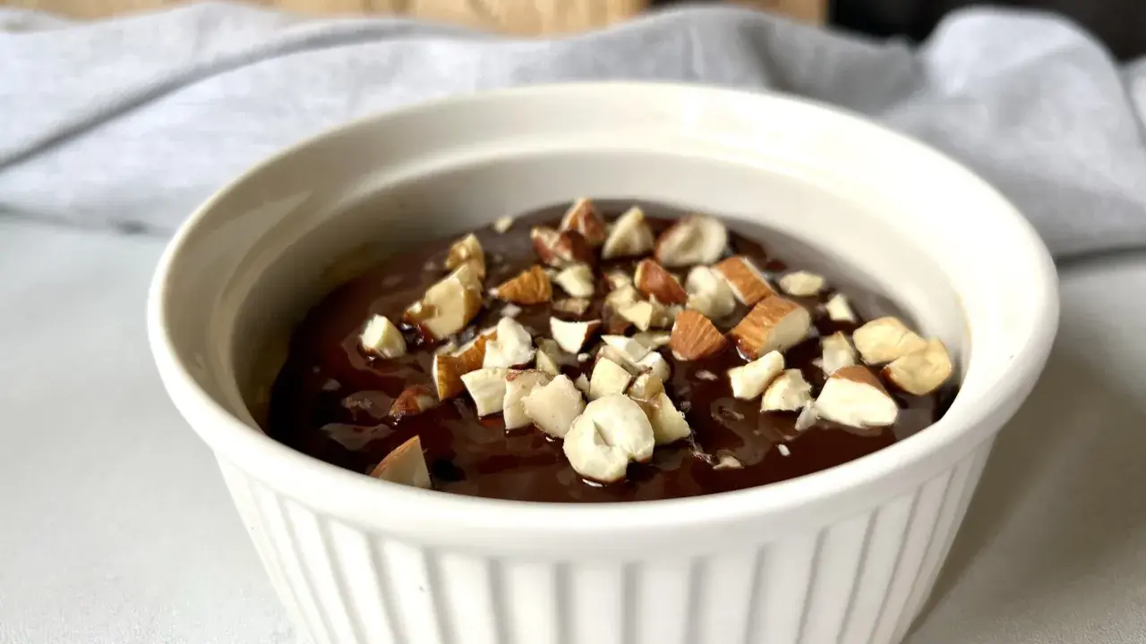 Czekoladowy deser low carb posypany orzechami w białej miseczce.