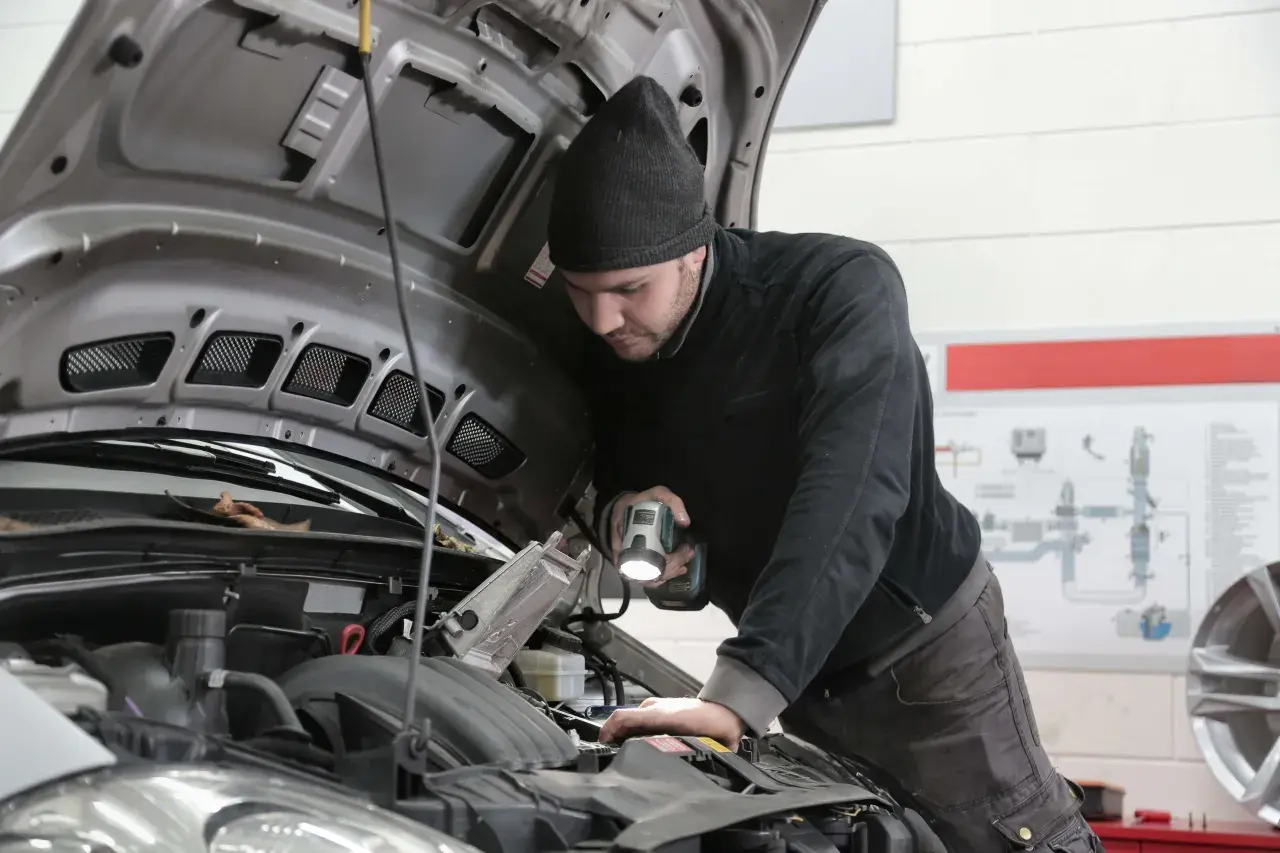 Mechanik z latarką bada silnik, szukając problemu z przegubem.