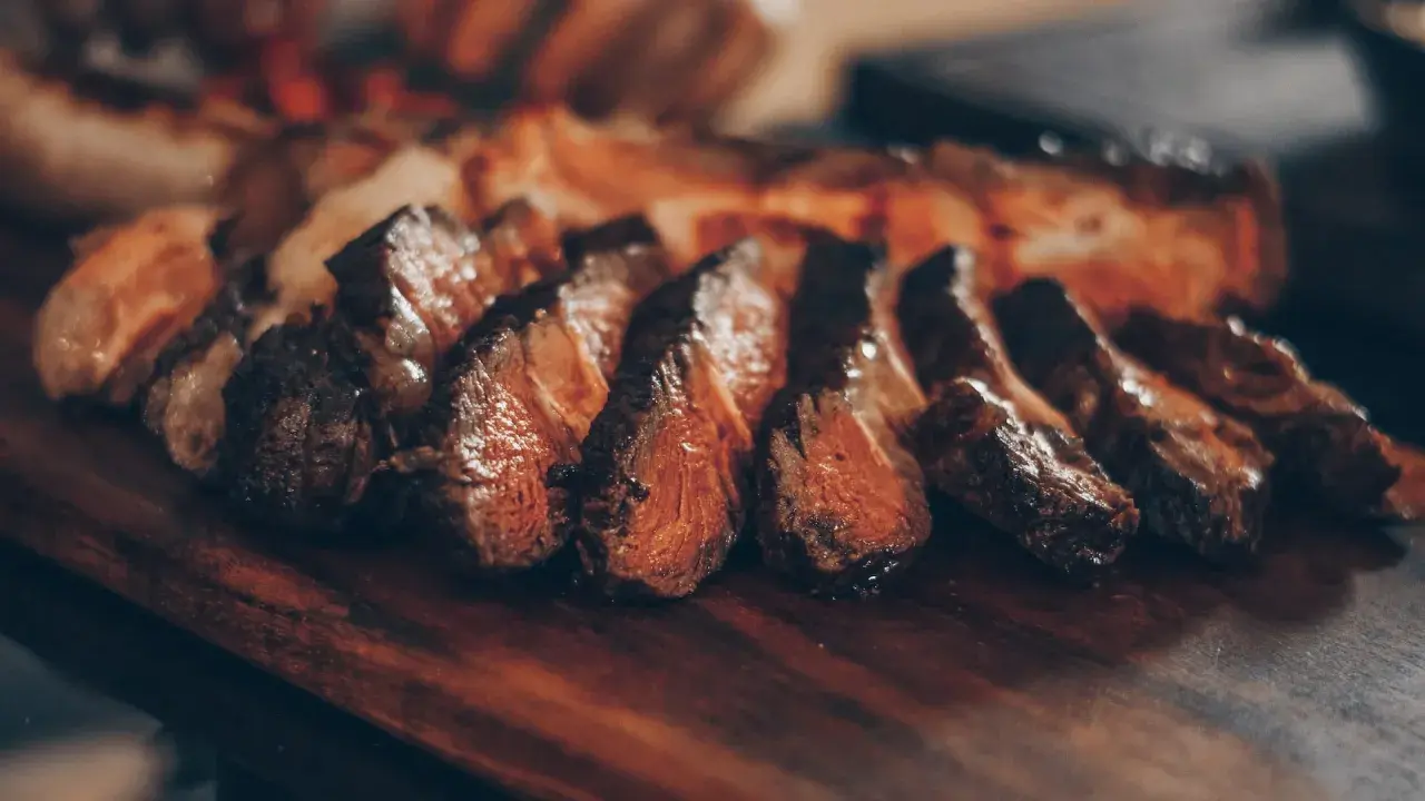Tranches de viande juteuse sur une planche en bois. Idéal pour savoir quel vin servir avec une pierrade de viande.