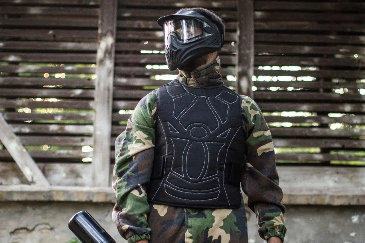 Gracz w kamizelce ochronnej i masce, gotowy do gry. Tak się ubiera na paintball, by czuć się bezpiecznie i komfortowo.