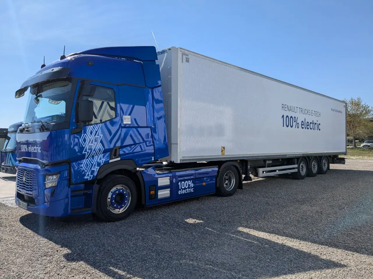 Un camion renault electrique bleu vif, avec une remorque blanche arborant le message "100% electric".