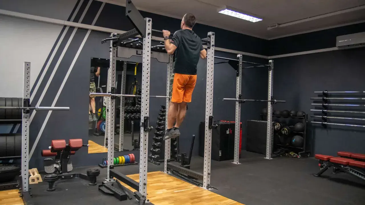 Mężczyzna wykonuje podciąganie na drążku w siłowni. To element skutecznego powerlifting plan treningowy.