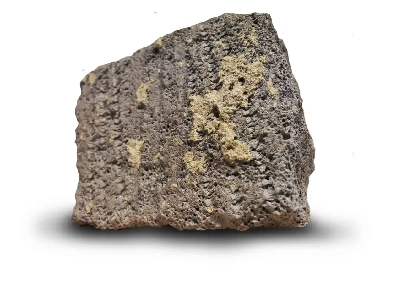En bit porös, mörkgrå sten med ljusare gula partier. Så här ser blåbetong ut, en lätt och isolerande sten.