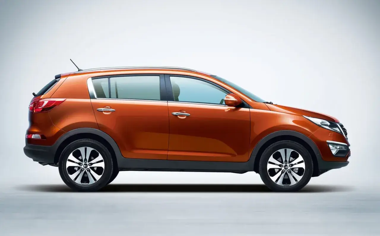 Pomarańczowy Kia Sportage 2014, widok z boku, gotowy na przygodę.