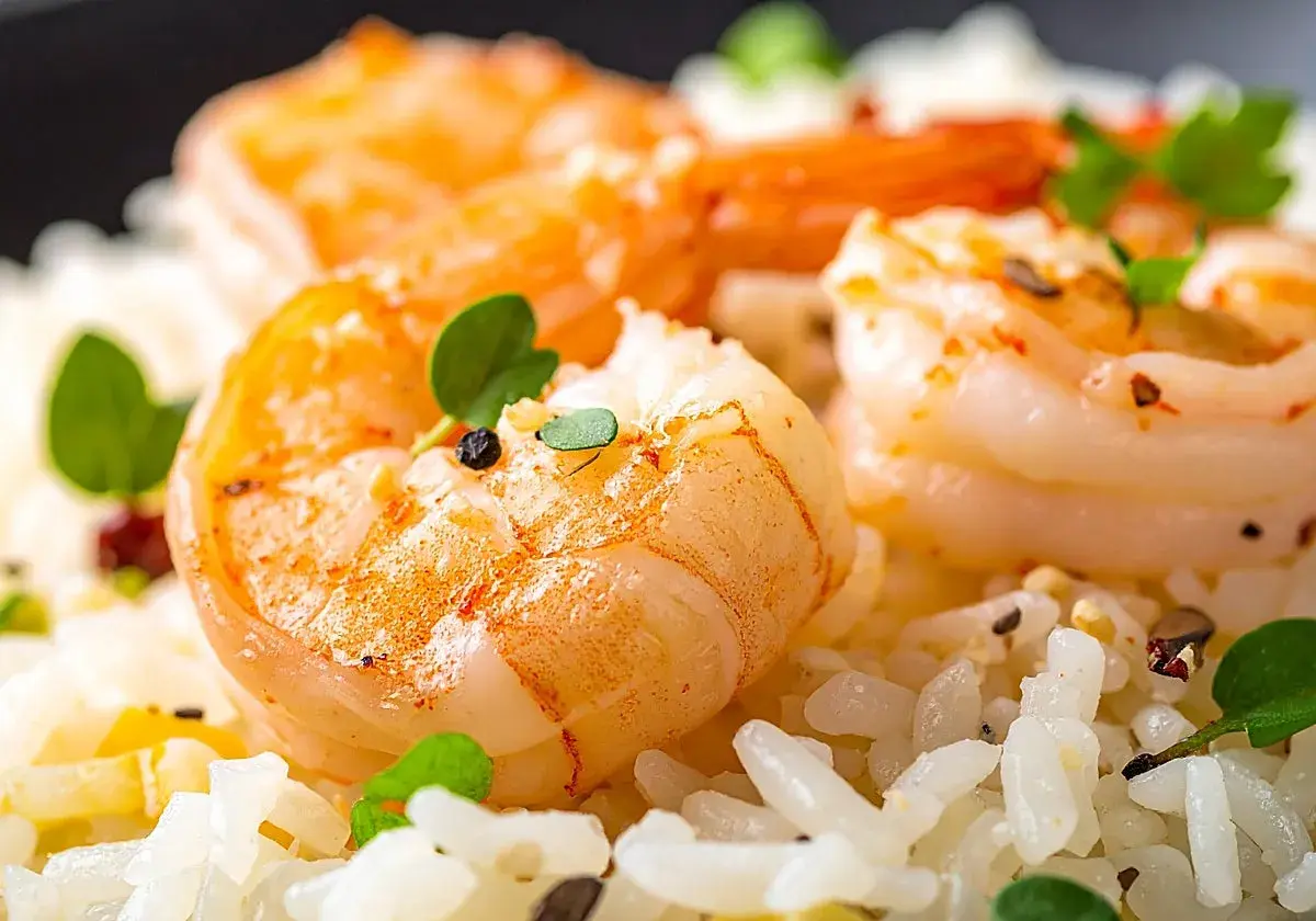 Delicioso arroz con gambas y verduras, adornado con hierbas frescas y granos de pimienta.