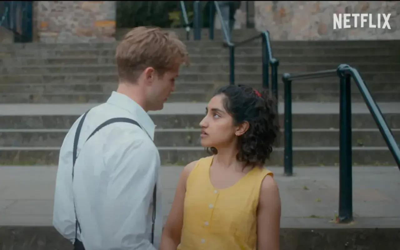 Un ragazzo e una ragazza si guardano intensamente su una scalinata. Le loro espressioni suggeriscono un momento carico di emozioni, forse l'inizio di una storia che troverà spazio nelle recensioni di un giorno.