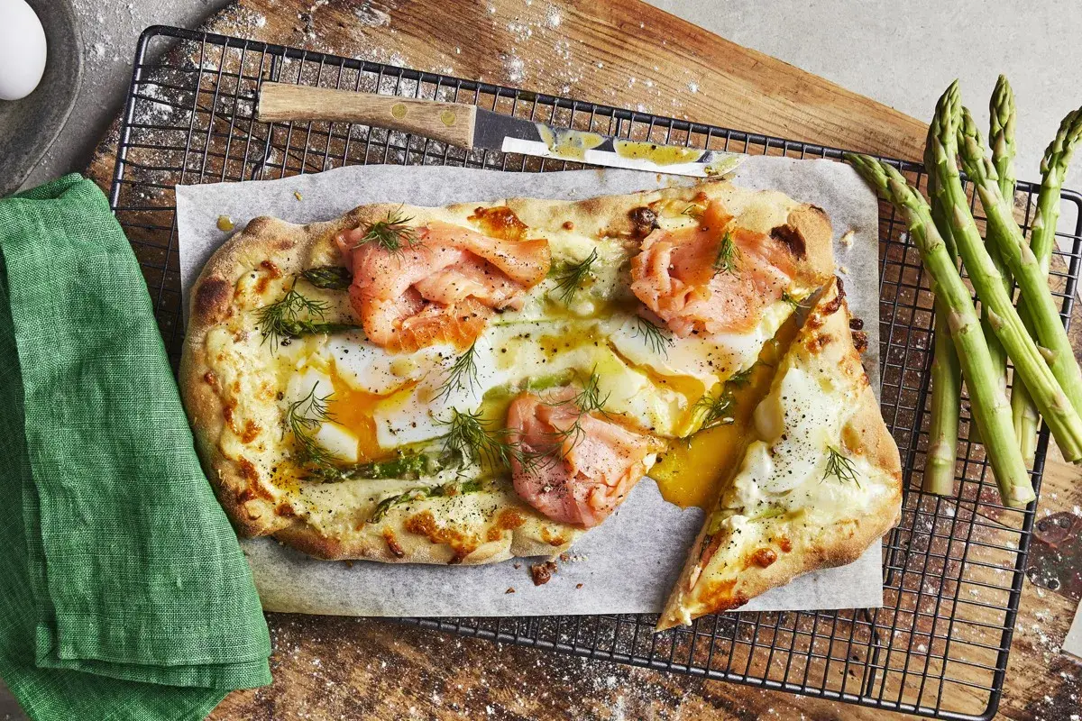 En läcker pizza med rökt lax, ägg och sparris, som en italiensk dröm på en tallrik.