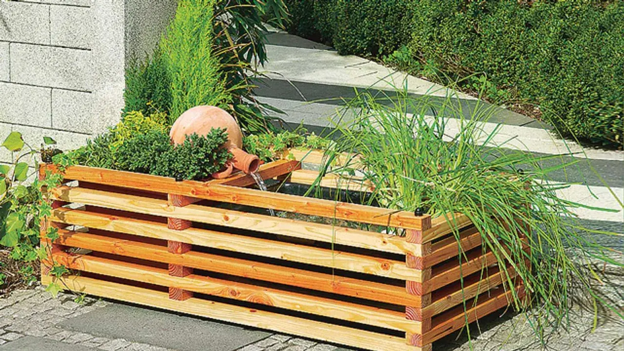 Ein **gartenbrunnen selber bauen** ist mit diesem rustikalen Holzgefäß und der Terrakotta-Kugel leicht gemacht. Wasser plätschert beruhigend.