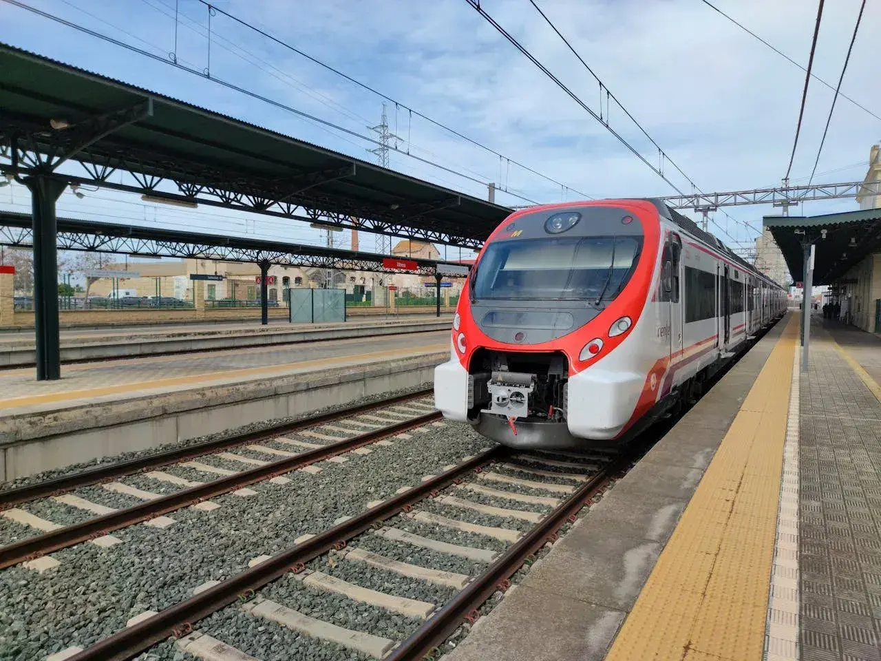 Nowoczesny pociąg Renfe czeka na pasażerów na stacji kolejowej.