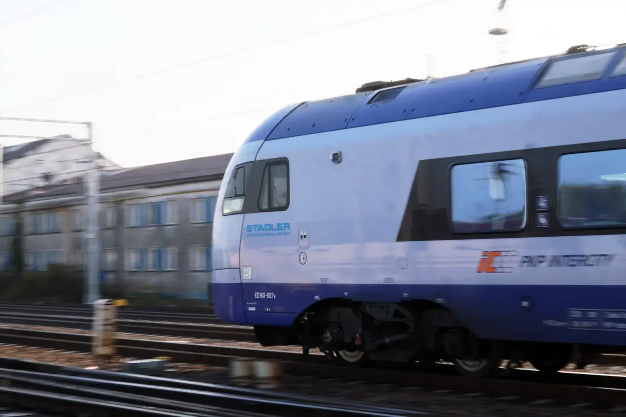 Pociąg PKP Intercity Stadler ED160-007a mija budynek w ruchu. Może to być podróż z Chełma do Krakowa.
