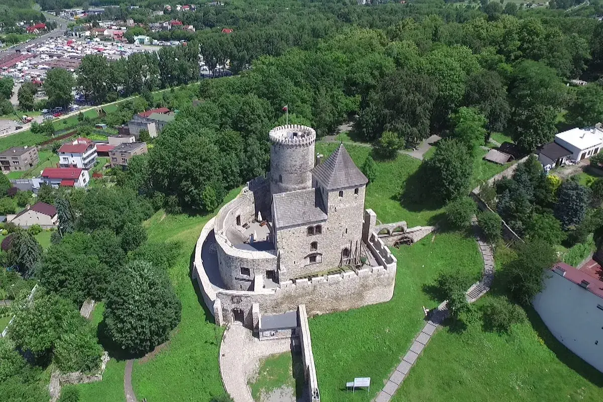Zamek w Będzinie, majestatyczna warownia z kamienia, góruje nad zielonym krajobrazem.