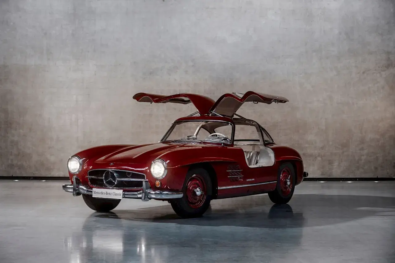 Czerwony Mercedes Gullwing z otwartymi drzwiami, ikona motoryzacji, prezentuje swoje klasyczne linie.