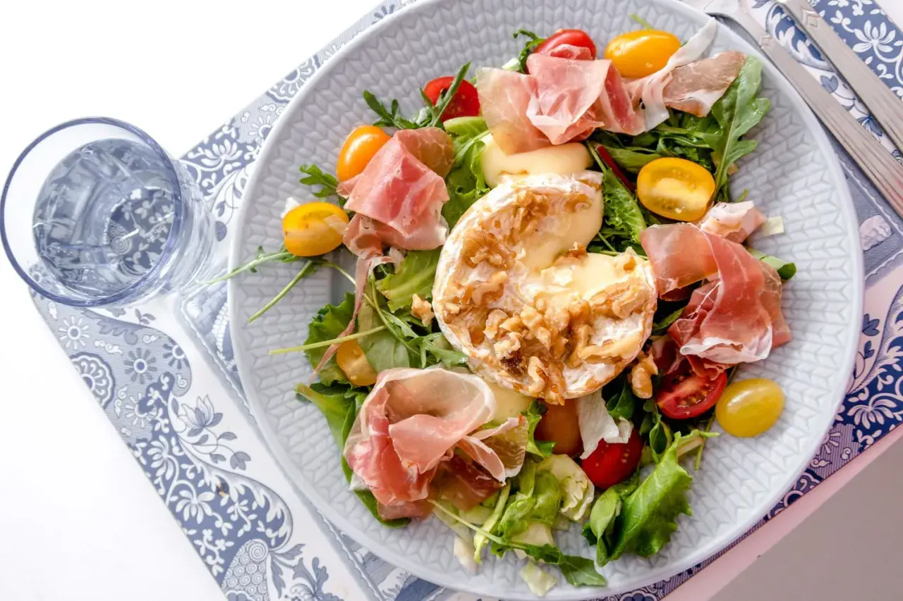 En härlig sallad med prosciutto, krämig ost med nötter, körsbärstomater och gröna blad. En perfekt sommarrätt.