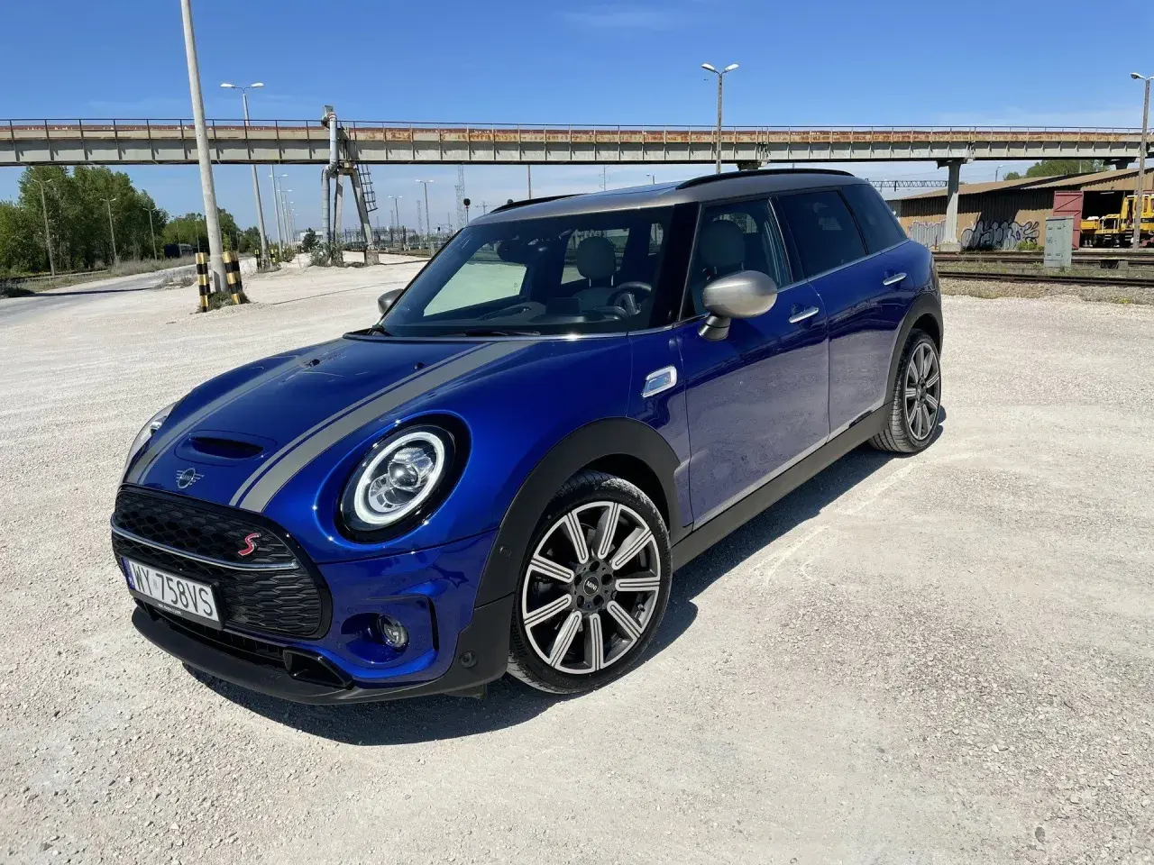 Niebieski Mini Cooper Clubman S z szarymi pasami na masce. Wiele osób chwali sobie jego zwinność i styl, co potwierdzają liczne mini cooper opinie.