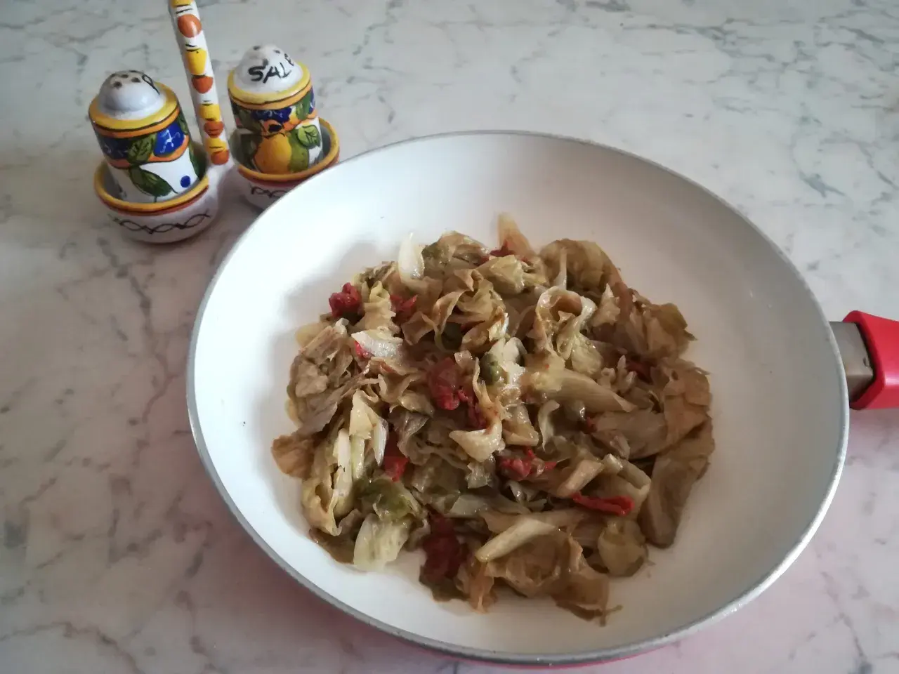 Insalata iceberg cotta in padella con pomodori secchi. Un piatto semplice e gustoso.