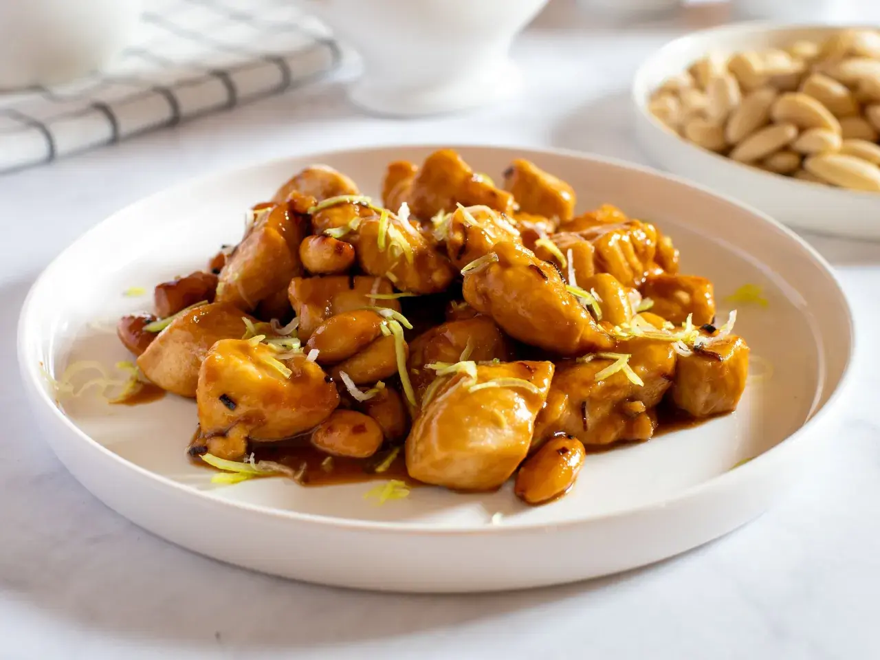 Un invitante piatto di pollo alle mandorle, lucido e saporito, guarnito con erba cipollina.