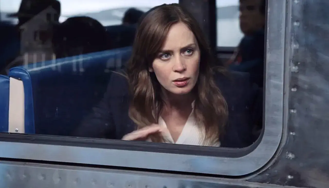 Emily Blunt w filmie, zamyślona, patrzy przez okno pociągu.