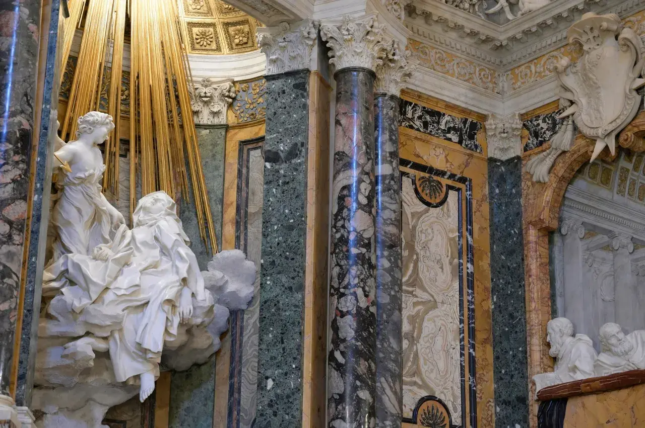 La Cappella Cornaro: un angelo colpisce Santa Teresa con una freccia dorata, circondata da marmi preziosi e decorazioni barocche.