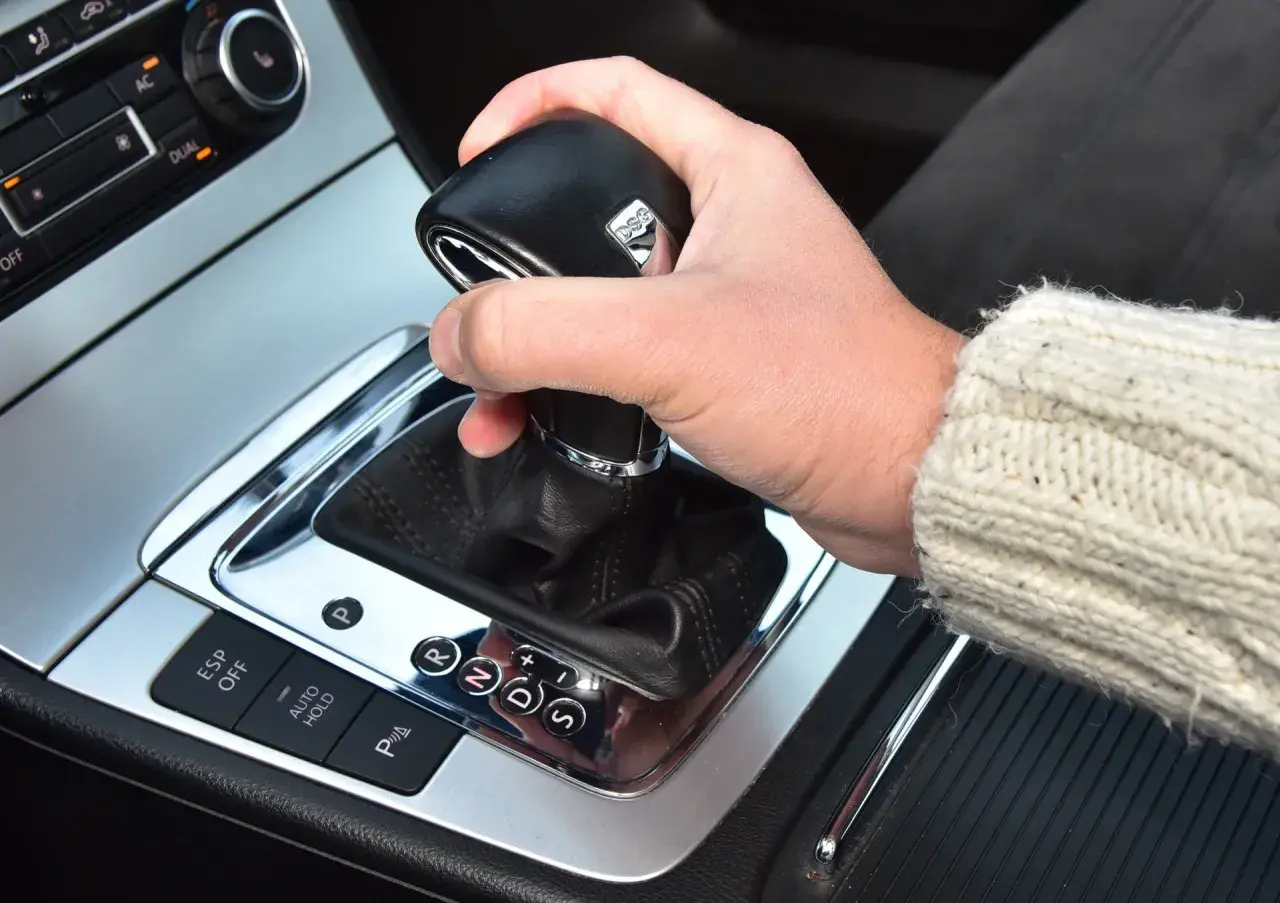 Dłoń na lewarku DSG, pokazująca jak jeździć automatem. Widoczne przyciski ESP, Auto Hold i wybór biegów P, R, N, D, S.