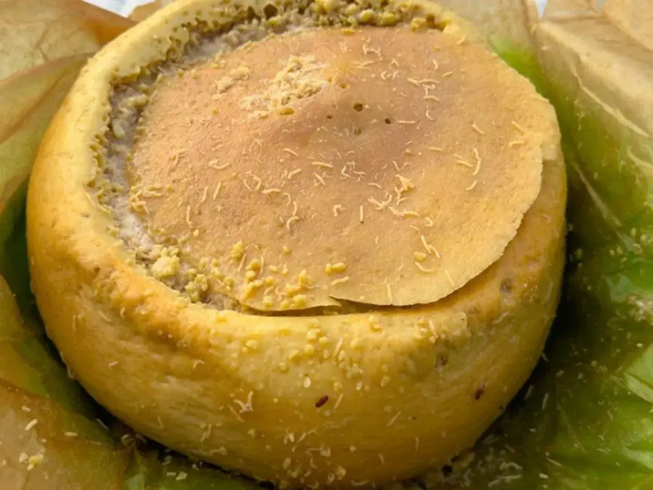 Formaggio casu marzu, con la sua crosta dorata e il ripieno cremoso, pronto per essere gustato.