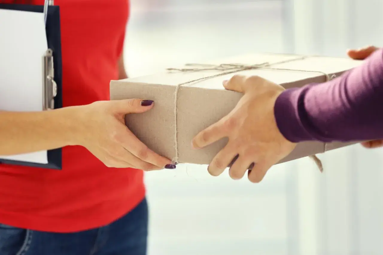 Kurier DHL przekazuje paczkę, na której widnieje napis "ostrożnie szkło".