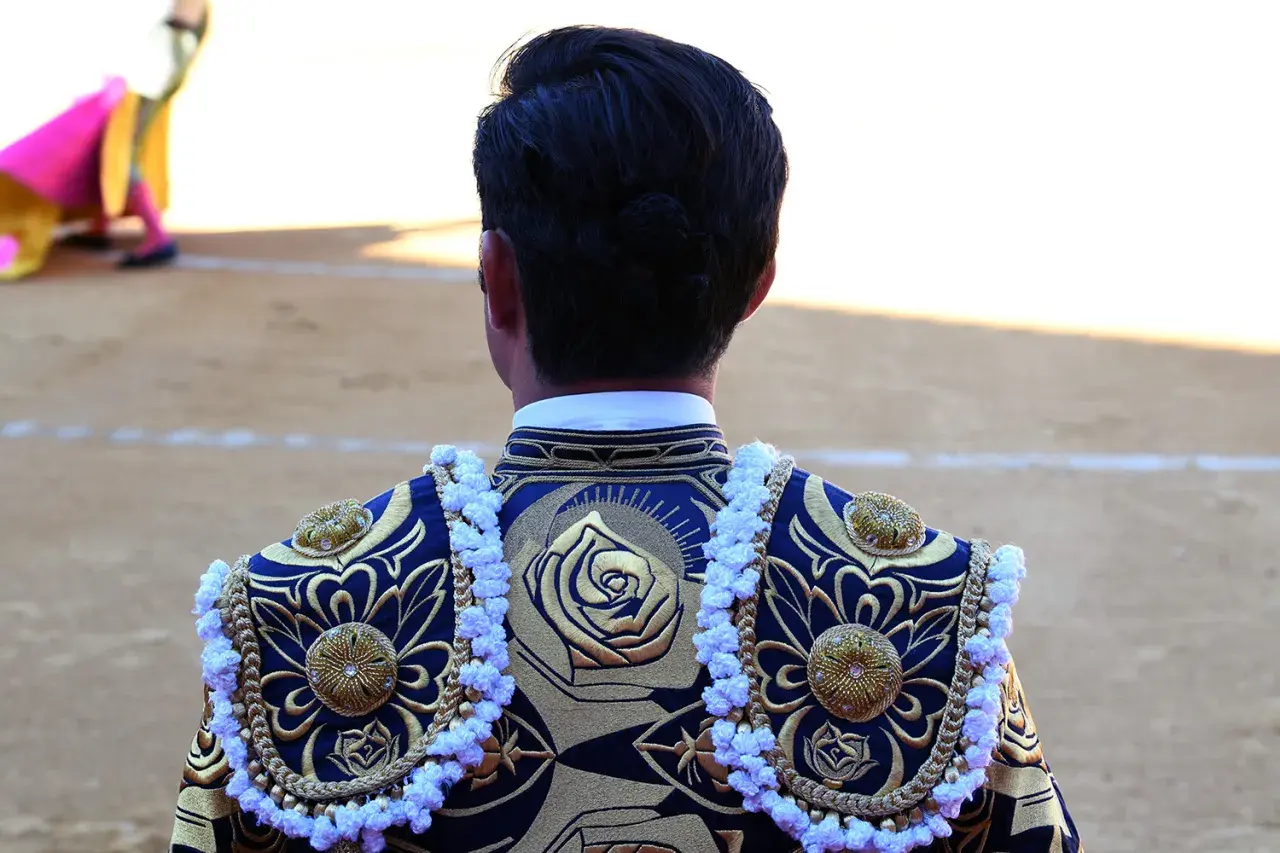 Detalle de la espalda de un torero con bordados dorados y azules, mostrando los vibrantes colores taurinos.