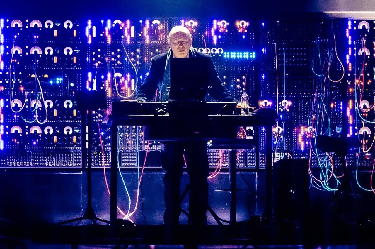 Hans Zimmer w Krakowie, na tle świecącej ściany syntezatorów i kabli, tworzy magiczną atmosferę.