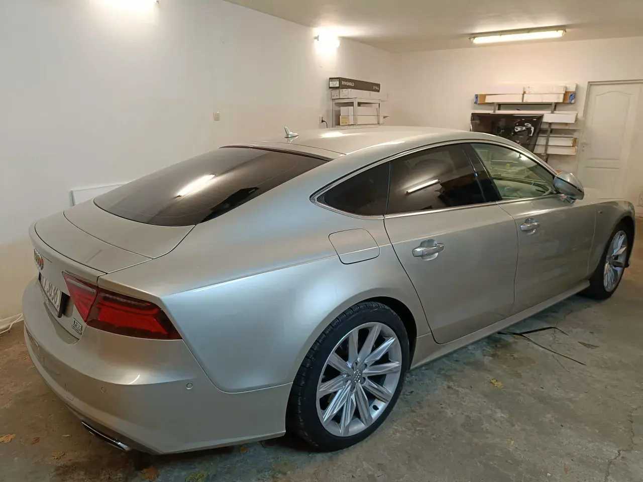 Srebrne Audi A7 z przyciemnione szyby stoi w garażu.