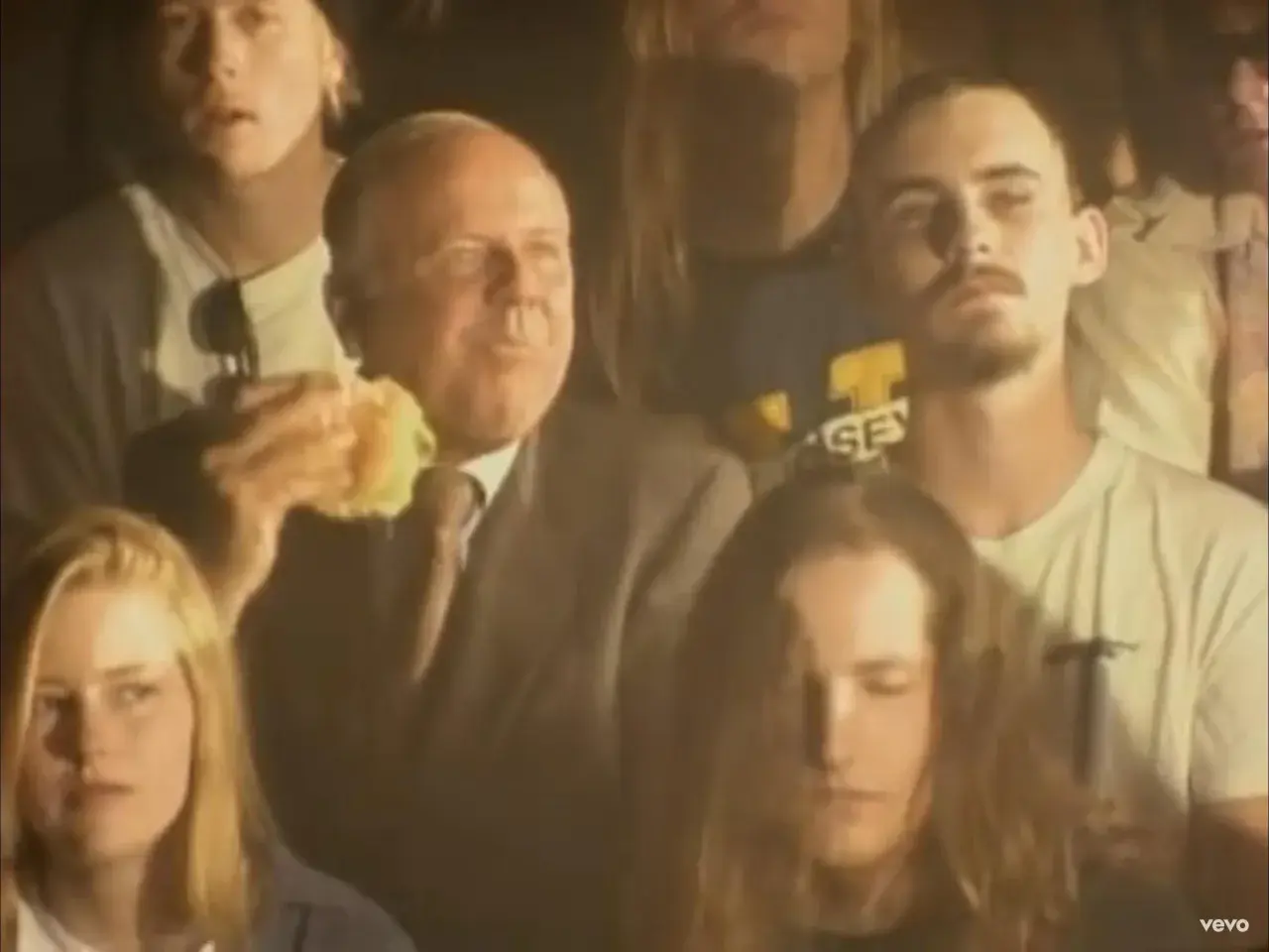 Tłum ludzi, wśród nich starszy mężczyzna jedzący burgera. Atmosfera jest mroczna, ale czuć w niej energię, jakby to był koncert, który pachnie nirwaną.