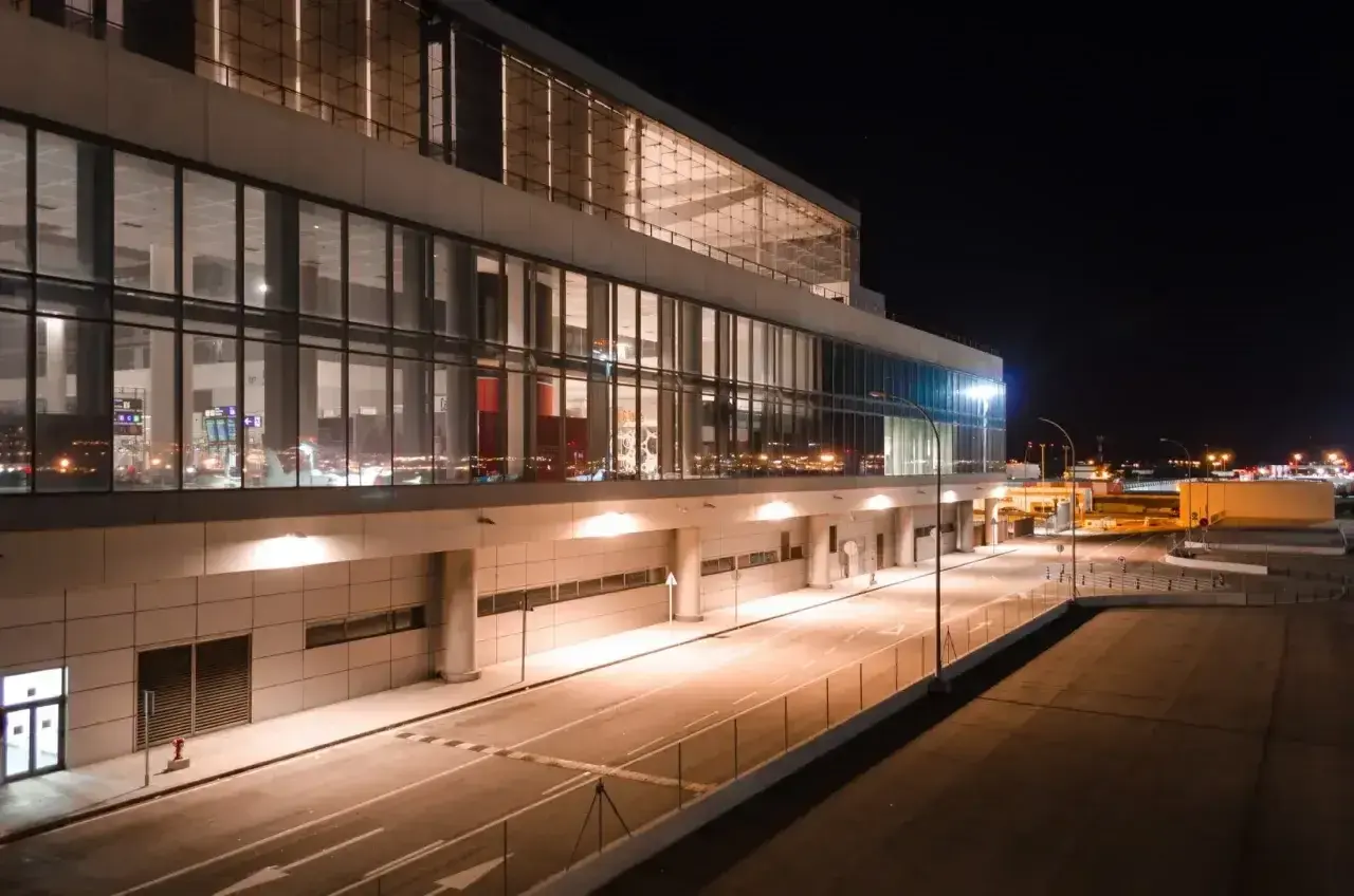 Nowoczesny terminal lotniska w nocy, z podświetlanymi oknami i drogami. Wygląda jak marzenie o podróży do Marbelli.