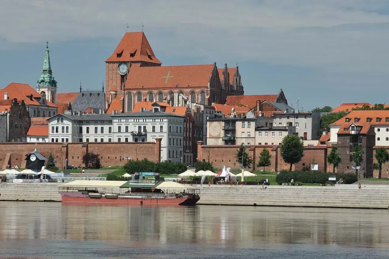 Widok na średniowieczny zespół miejski Torunia z Wisły. Widać katedrę, mury obronne i kamienice.