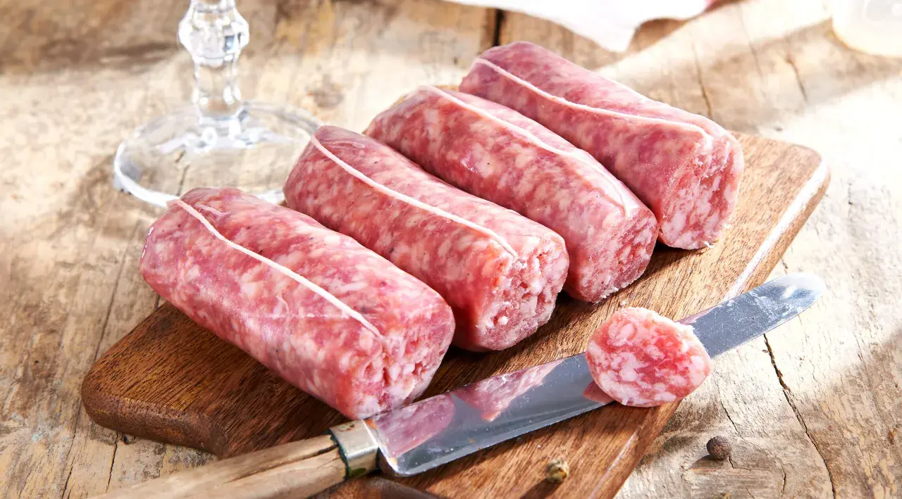 Frische Salsiccia-Würste auf Holzbrett, Messer mit Scheibe. Die korrekte Salsiccia Aussprache ist wichtig für den Genuss.
