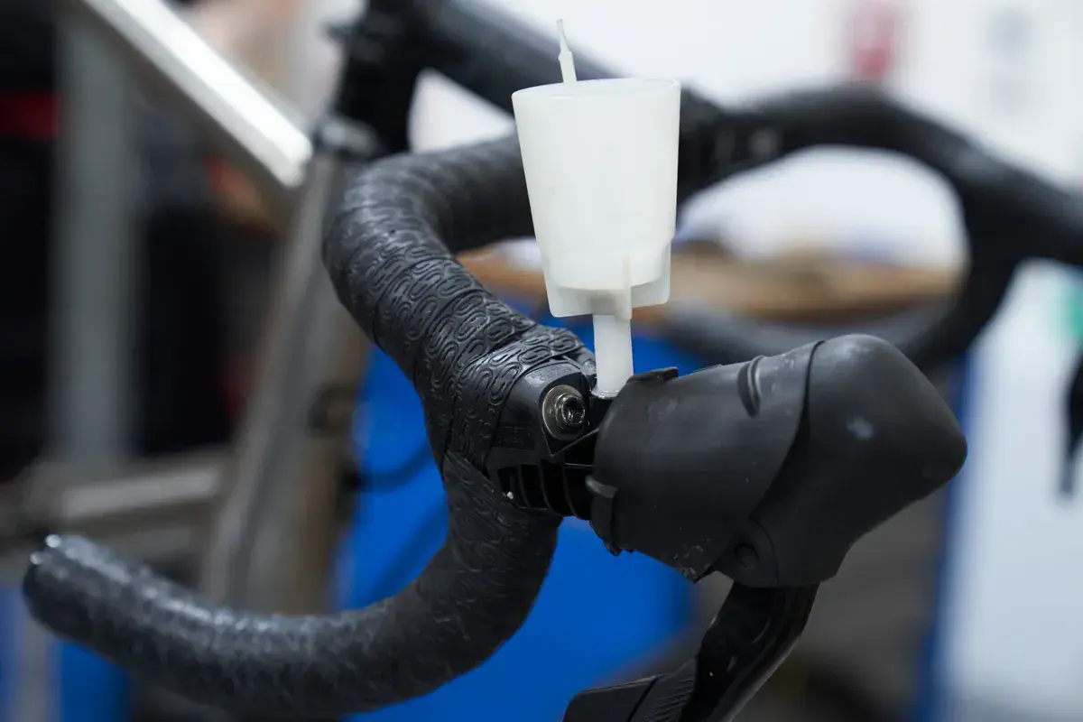A white funnel attached to a bicycle handlebar, part of an easy way to bleed brakes.