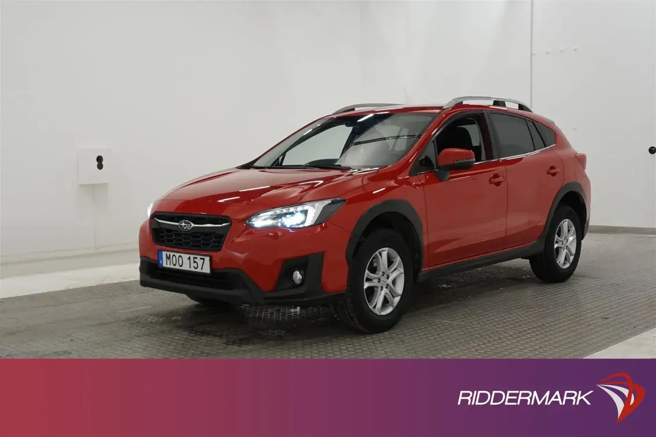 A red Subaru XV parked indoors, with its headlights on.