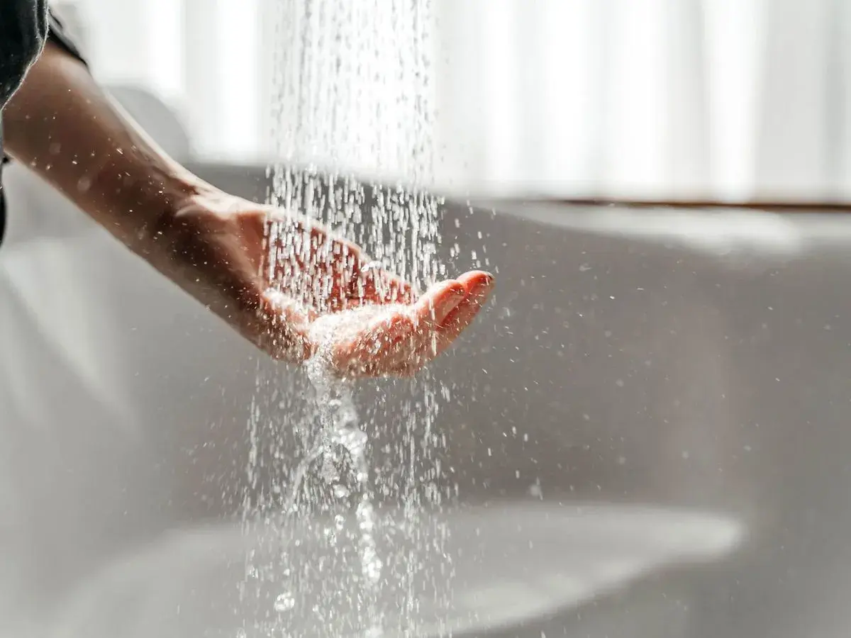 Hand fängt Wasser auf. Mögliche Legionellen im Wasser können zu einer Mietminderung führen.