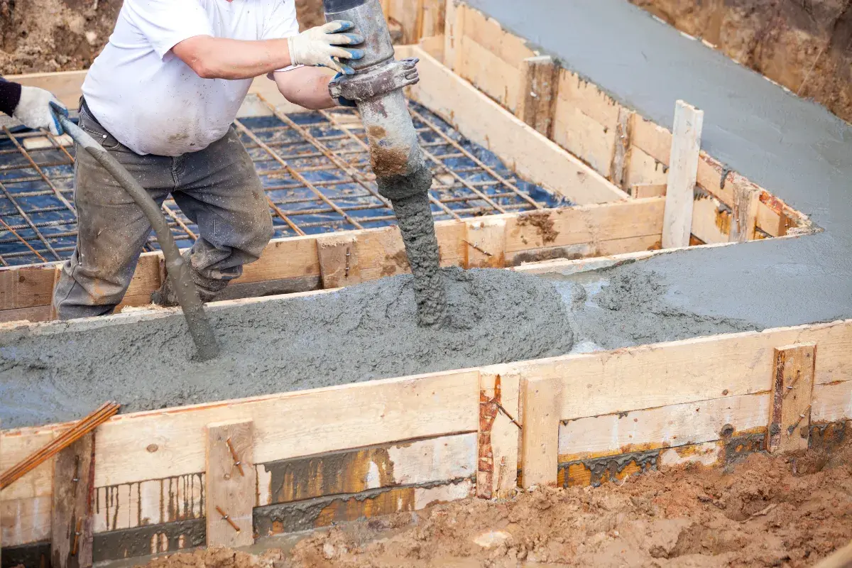 Betoniarka wylewa beton do drewnianej formy, tworząc wylewkę.