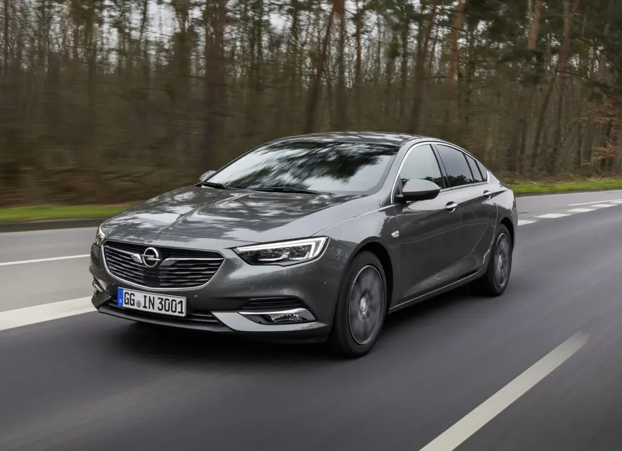 Grå Opel Insignia kör på en väg genom en skog. Kanske ett opel insignia problem med att hitta rätt väg?
