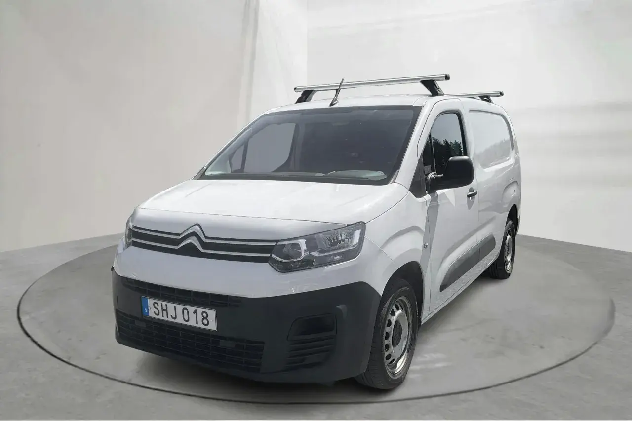 Vit Citroën Berlingo, en pålitlig begagnad transportbil med takräcke, redo för nya äventyr.
