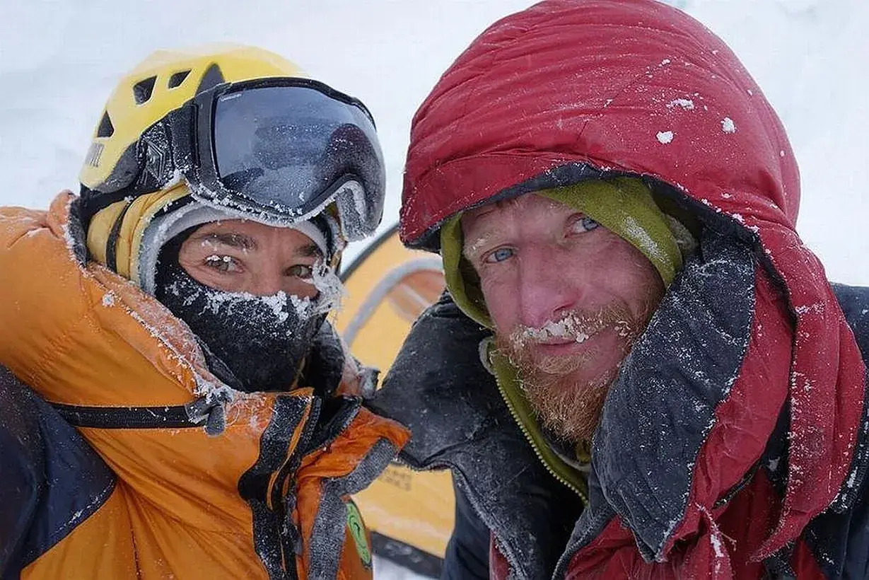 Tomasz Mackiewicz und ein Bergsteigerkollege, bedeckt mit Schnee, blicken in die Kamera.