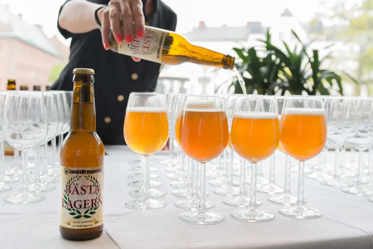 Une personne verse la bière suédoise connue, Bästa Lagern, dans des verres.