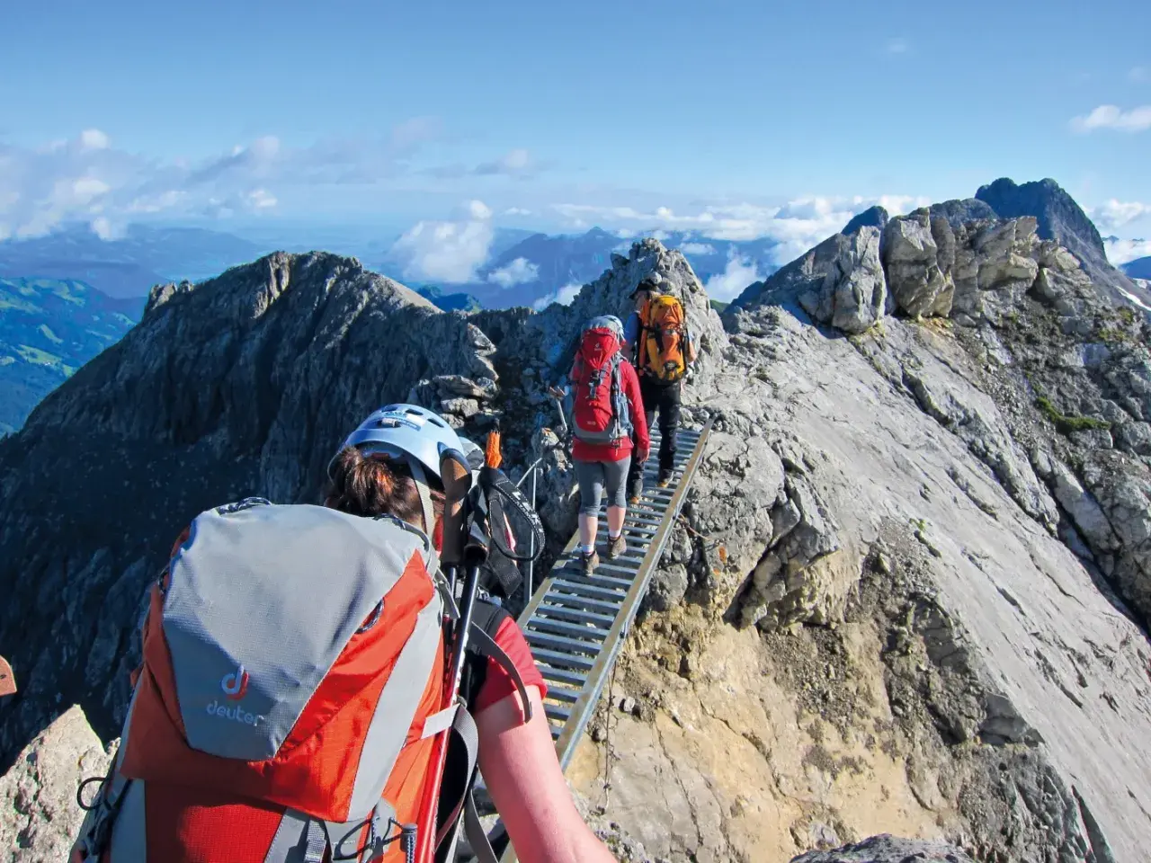 Drei Wanderer auf einer Hängebrücke während einer 5-tägigen Alpenwanderung. Die Aussicht ist atemberaubend.