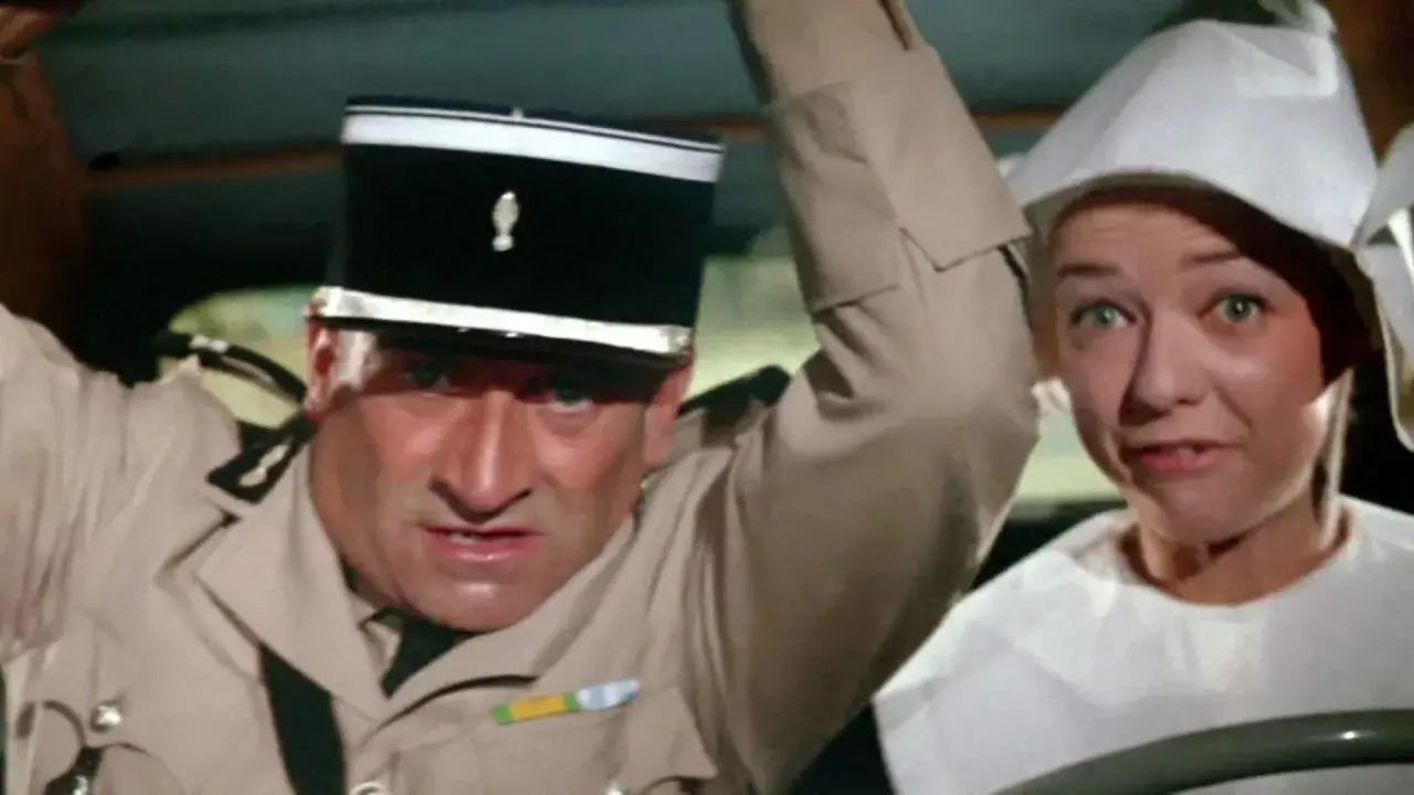 Louis de Funès w filmach, w mundurze żandarma, z przerażoną miną obok kobiety w białym nakryciu głowy.